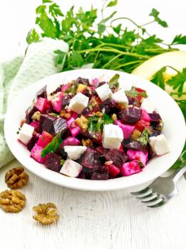 Salad with beetroot, feta cheese, apple, walnuts, parsley, seasoned with balsamic vinegar and olive oil in a plate, napkin against a light wooden board