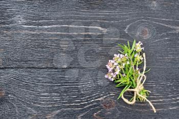 Bunch of fresh thyme with flowers on a black wooden board background