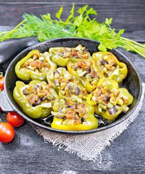 Sweet pepper stuffed with mushrooms, tomatoes, zucchini, eggplant and onions, seasoned with wine, garlic, thyme and spices in a frying pan on sackcloth against wooden board