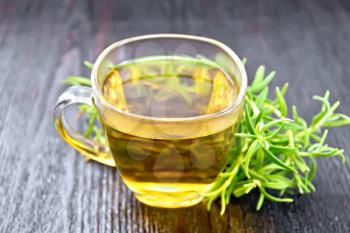 Rosemary herbal tea in a cup on a dark wooden board background