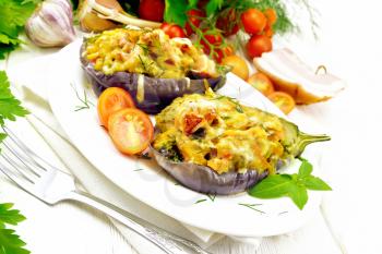 Stuffed eggplants with smoked brisket, tomatoes, onions, carrots with garlic, cheese and herbs in a plate on a kitchen towel on wooden board background