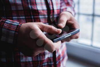 The man is using a smartphone. Modern mobile phone in hand.