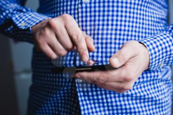 The man is using a smartphone. Modern mobile phone in hand.