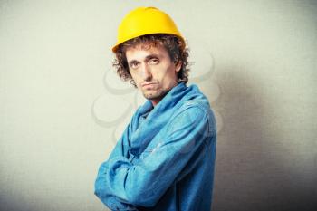 Curly man in a yellow hard hat. On a gray background.
