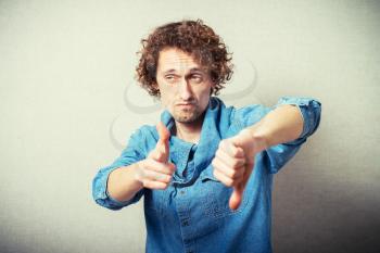 Curly man index finger at the camera and gesture badly. On a gray background.