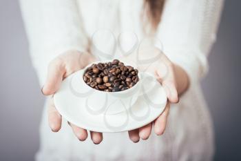 girl holding a cup of coffee beans