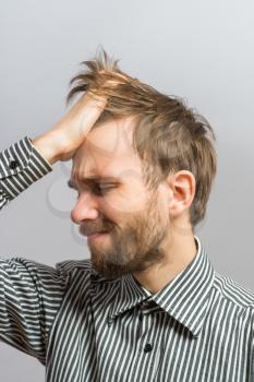 Closeup of angry young man tearing his hair. He is expressive and isolated on a white background
