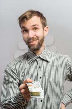 Portrait of smiling young man holding fanned US paper currency