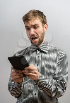 shocked man holding tablet pc and screaming. studio shot over dark background