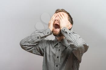 portrait one sad man standing near a  wall and covers his face