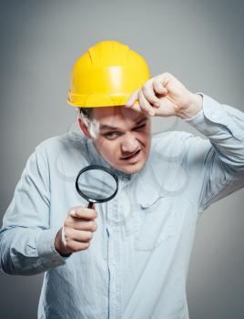 Asian engineer man wear hardhat  hold a magnifying glass focus on the glass isolated 