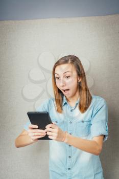 girl looking into a tablet and shocked