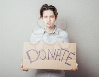a man with an inscription on cardboard donate