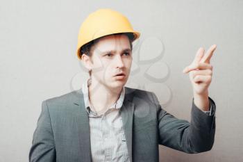 Young builder in helmet pointing finger
