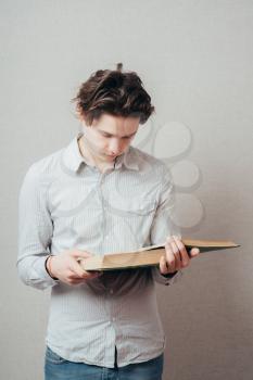 Portrait of young man  reading isolated over grey background