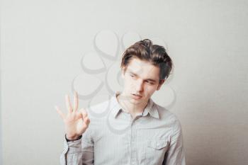 Portrait of a smiling handsome young man gesturing ok sign