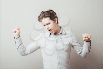 handsome excited man happy  hold arm hands fist raised up gesture, young guy wear shirt