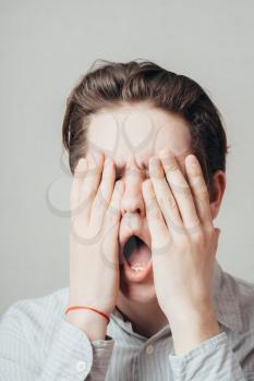 young man covers his face