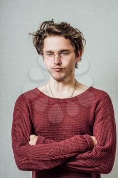 Portrait of handsome young man standing with his arms crossed against grey background with copy space. male fashion model looking at camera.