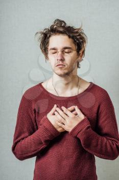 The man in glasses hands together praying. On a gray background.