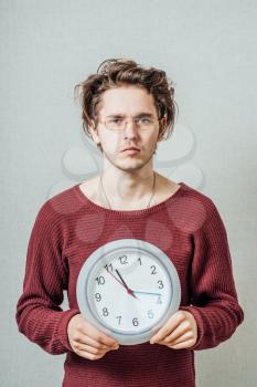 portrait of a man holding a clock against a grey background