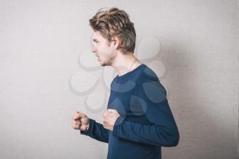 young man angry, on a gray background.