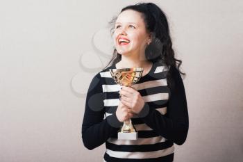 A woman with a golden cup victory. Gray background.