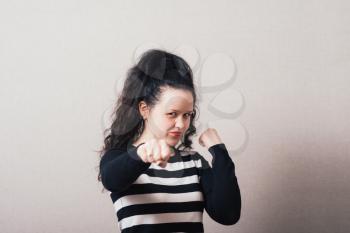 Woman angry fists. Gray background.