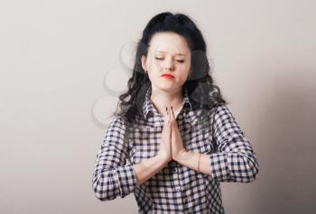 Closeup portrait of a young woman praying, isolated on a gray background