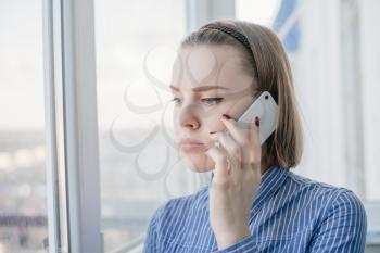 Business woman speaking phone and looking through window with city background