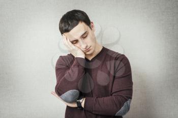 Young Man wants to sleep. Put his head in his hands