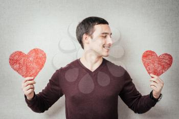 A young man holding two a red heart in his hands