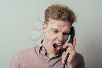 man shouts talking on landline phone
