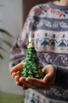 hands hold a christmas candle as fur-tree form