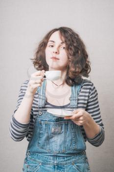 girl drinking coffee, dressed in overalls