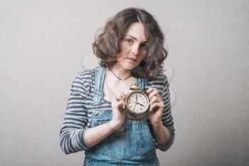 beautiful woman holding alarm clock in hand, dressed in a suit