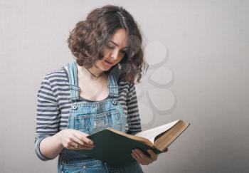 girl with big book in hand in hand on a gray background