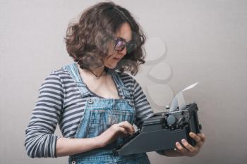Young attractive secretary writing with an old typewriter. Conceptual image.