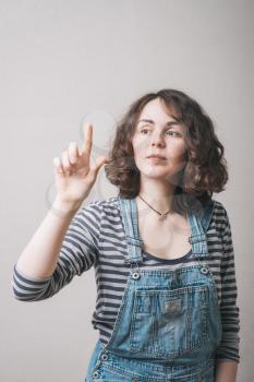 A beautiful young adult woman touching in the air with one finger