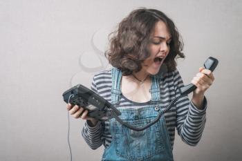 Young woman   yelling at telephone handset that she is holding in her hand