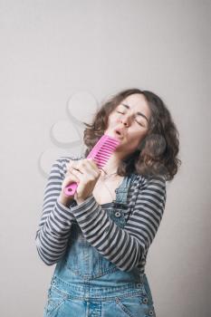 girl  sings, using a hairbrush for hair instead of a microphone