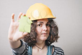 girl in the construction helmet and suit holding a cardboard house