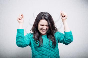 pretty young woman raising a fist in celebration, triumph, excitement