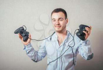 Happy young man in winning pose wearing shirt holding video game joystick.