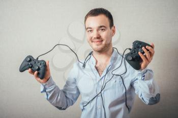 Happy young man in winning pose wearing shirt holding video game joystick.