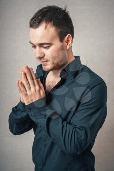 A man prays. On a gray background.