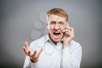 portrait of an angry young man shouting using a mobile 