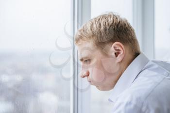 Young businessman looking out of a window and thinking