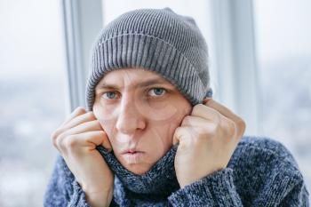 Young man feeling cold in flat near the window