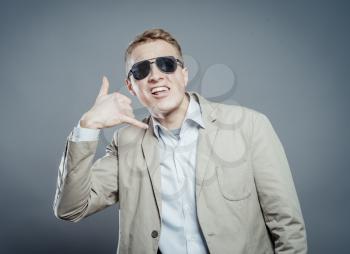 Young man in sun glasses. Laughing shows call me. gesture. photo shoot.